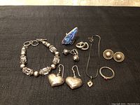 Full set of sterling silver jewelry including bracelet, multiple pairs of earrings, and a ring, shown on a black fabric background.