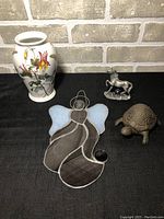 Overview of four items: botanical vase, stained glass angel, cast iron turtle, unicorn figurine.