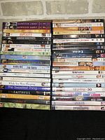 Photo showing stacked DVDs in good used condition with visible movie titles including Downton Abbey, Duplicity, Hope Springs, The Sound of Music, and more.