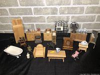Overview of the miniature furniture collection set against a brick wall background, showing various pieces including furniture and household appliances.