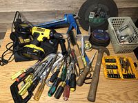 Various used hand tools including screwdrivers, pliers, wire cutters, scissors, a hammer, and a DeWalt cordless drill with charger and batteries. The drill chuck is noted as broken.
