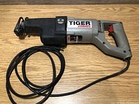 Side view of Porter Cable Tiger Saw Model 737 reciprocating saw laid on wooden surface, showing quick-change blade clamp and trigger handle.