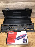 Open black toolbox with large black tool organizer tray inside, showing multiple tool slots, rotary tool kit box placed on top.