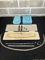 Full lot of vintage silver and pearl jewelry displayed on black surface including chain necklaces, silver ring, earrings, and boxes.