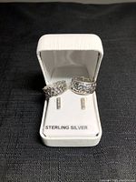 Two sterling silver rings and a pair of rectangular stud earrings displayed in white box with 'STERLING SILVER' label