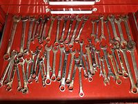 Red toolbox drawer with a variety of combination and open-end wrenches showing rust and wear.