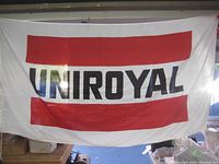 Uniroyal flag with large red stripes and black text on white fabric, hanging indoors