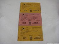 Four Canadian WWII ration books arranged to show different covers, two yellow and one pink visible.