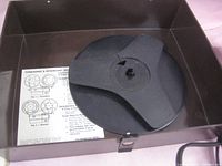 Top open view of the projector showing the reel mount and threading instructions inside lid.