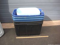 Black and blue stacked plastic bins with three lids on top, bins show signs of use and need cleaning.
