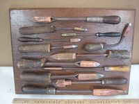 Wide top-down view of the soldering irons mounted on a wooden panel showing the variety and arrangement of tools.