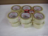 12 rolls of clear Vibac packaging tape stacked 6 on the bottom and 6 on top, wrapped in plastic.