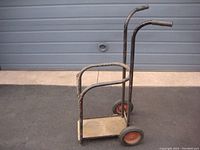 Full view of metal cart showing upright handles, base, wheels, and frame for holding tanks