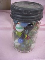 Full exterior view of clear Crown brand jar with dark metal lid, filled with colorful glass marbles.