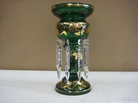 Full view of the dark green glass vase with gold leaf floral trim and hanging clear crystal spear prisms.