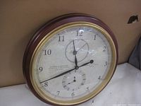 Front view of the large round wall clock mounted on a wall, showing main clock face with two time zones.