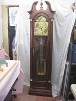 Full view of the wooden tall case grandfather clock standing 80 inches high with glass door showing pendulum and weights inside.