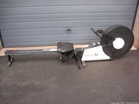 Full side view of Johnson A3 rowing machine showing rowing seat, rail, and air resistance flywheel at the end.