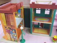 Multi-level Fisher-Price playhouse showing colorful illustrated interiors and exterior walls