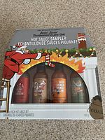 Box front showing all four bottles and festive holiday design with Santa delivering sauces.