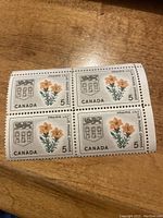 Front side of block of four Canadian stamps, showing floral design and provincial coat of arms with denomination of 5 cents.