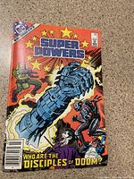 Front cover of the 1984 DC Comics Super Powers #1 showing colorful comic art with characters Joker, Penguin, and a large robotic fist.