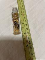 Photo of a small jar labeled 'Lucky Strike Pure Gold' next to a measuring tape showing height about 2.5-2.75 inches.