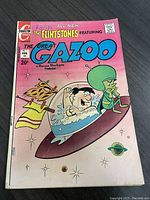 Front cover showing Fred Flintstone and The Great Gazoo on a pink background, with visible minor wear and a handwritten name 'Patty' on top.