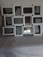Large white frame holding twelve individual glass picture slots