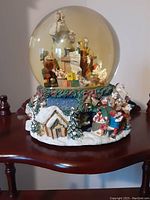 Christmas snow globe showing Santa, elves, and workshop scene inside glass globe with detailed winter base