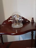 Glass dome decoration with flower, butterfly, and gold elements on round base