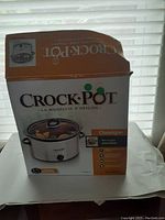 Box of Crock-Pot Classic slow cooker showing brand and product details in French and English with orange and white color scheme.