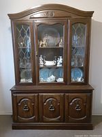 Front view of two-piece wooden hutch with glass display doors on top and wooden storage doors below
