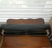 Photo showing a black curved fluorescent black light by Globe Electric on a wooden surface in front of window blinds.