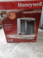 Box of Honeywell Warm Mist Humidifier featuring product image, specifications, and features like no filters to replace, 3.8 liters capacity and up to 24 hours run time.