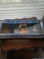 Original boxed packaging of the Nano Spy Copter showing the copter and remote inside with promotional graphics.