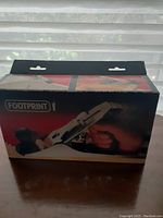 Original box showing Footprint brand hand plane tool with a hand gripping the tool and using it.