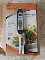 Front of packaged Taylor TruTemp instant read digital thermometer in blister pack, displaying thermometer and black protective sheath.