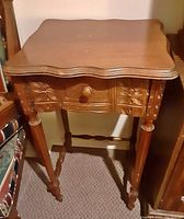 Photo showing vintage wooden entrance table with scalloped top, carved single drawer, and turned legs