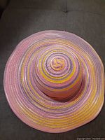 Top-down view of the multi-colored wide-brim hat showing concentric striped pattern in pink, yellow, and purple.