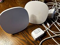 Two white Telus WiFi boosters on wood surface with assorted cords and plugs shown.