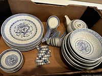Photo showing the full set of Asian blue and white tableware including plates, bowls, sauce bowls, teapot, multiple serving spoons, and chopstick holders.