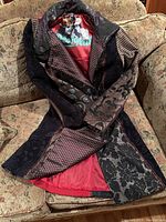 Patchwork patterned Desigual long coat displayed open showing red lining and inside brand label.