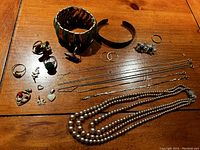 Overhead view of entire lot on wooden table showing bracelets, rings, earrings, chains, pendants and pearl necklace