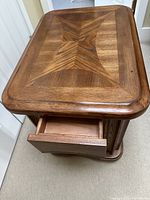 Wood side table showing open drawer and patterned top