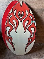 Skim board with abstract red and black flame-like pattern on cream base