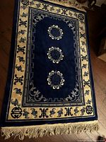 Full view of blue vintage Asian style rug showing three medallions and beige border with motifs