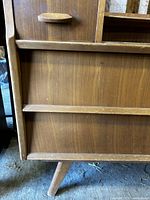 Close-up of the dresser leg, lower side panel, and drawer handle showing wear and finish deterioration.