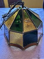 Side view of the vintage stained glass light fixture showing multicolored glass panels in green, amber, and textured clear glass with soldered metal joints.