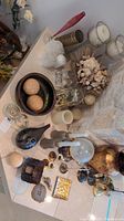 Various vases, bowls, ornamental balls, candles, and decor pieces grouped on floor near stone wall.